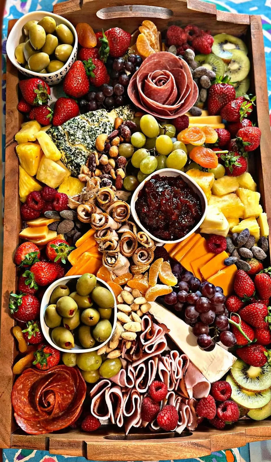 Colorful charcuterie board prepared by Yvette with fruit, cheese, meats, nuts, and olives
