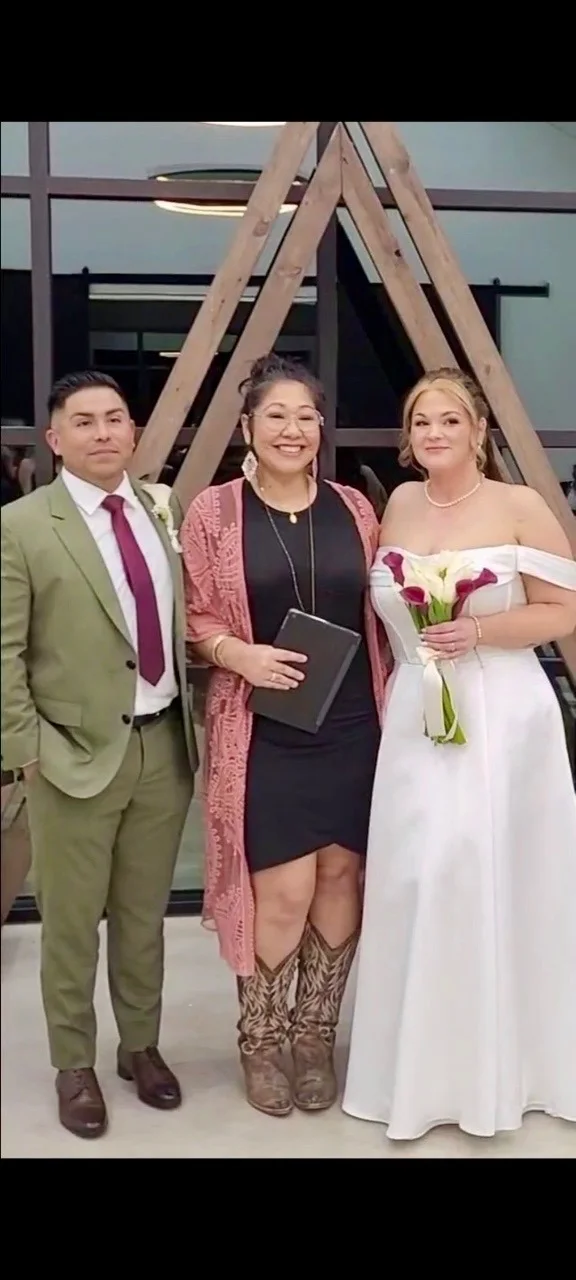 Gloria with a wedding couple in front of a wooden ceremony arch