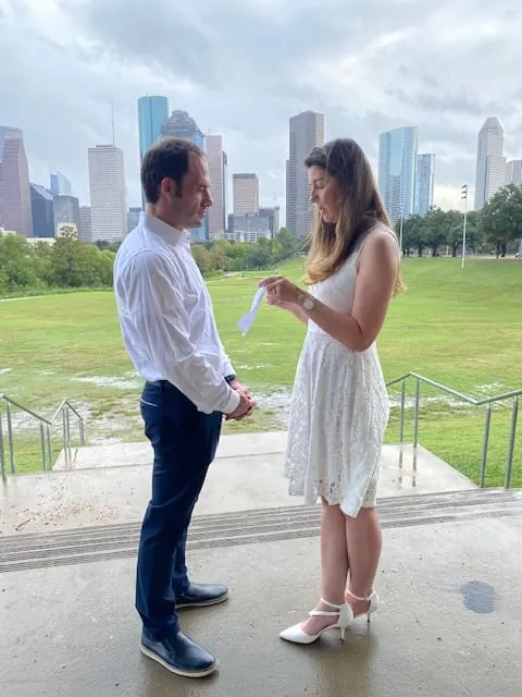 Couple exchanging vows outdoors with the Houston skyline behind them