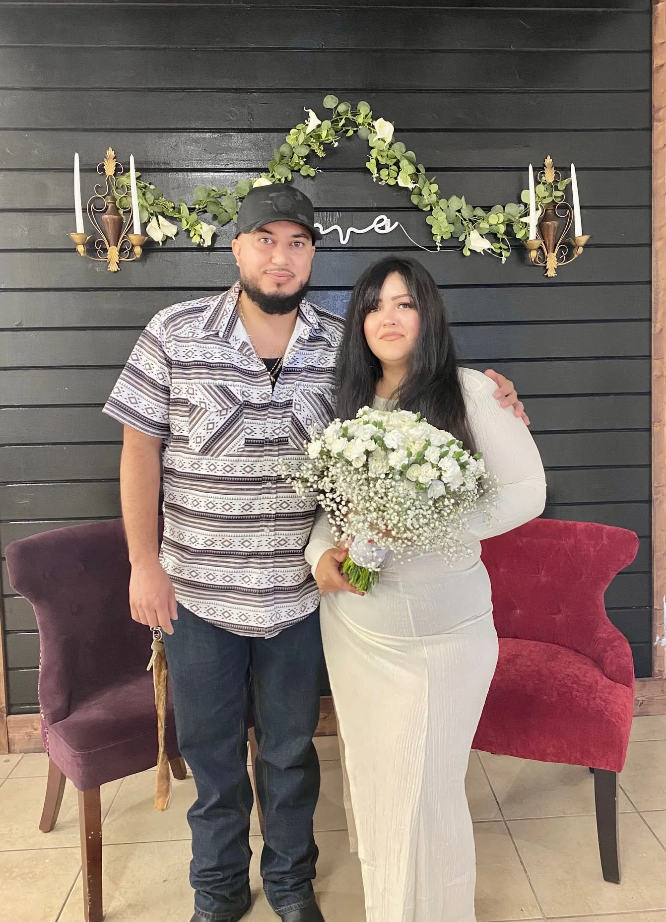 Newlywed couple standing together against the love backdrop at the new Twin Flames Heights office