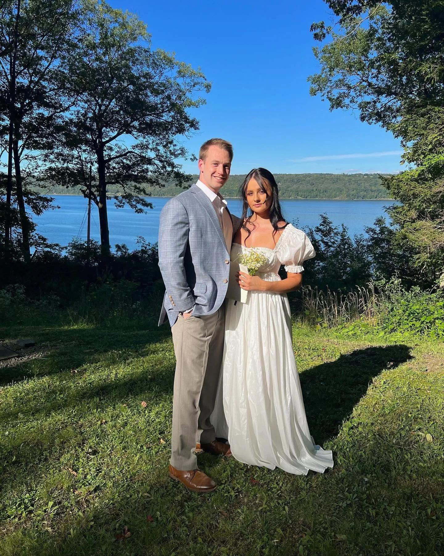 Newlywed couple standing together in a lakeside outdoor setting