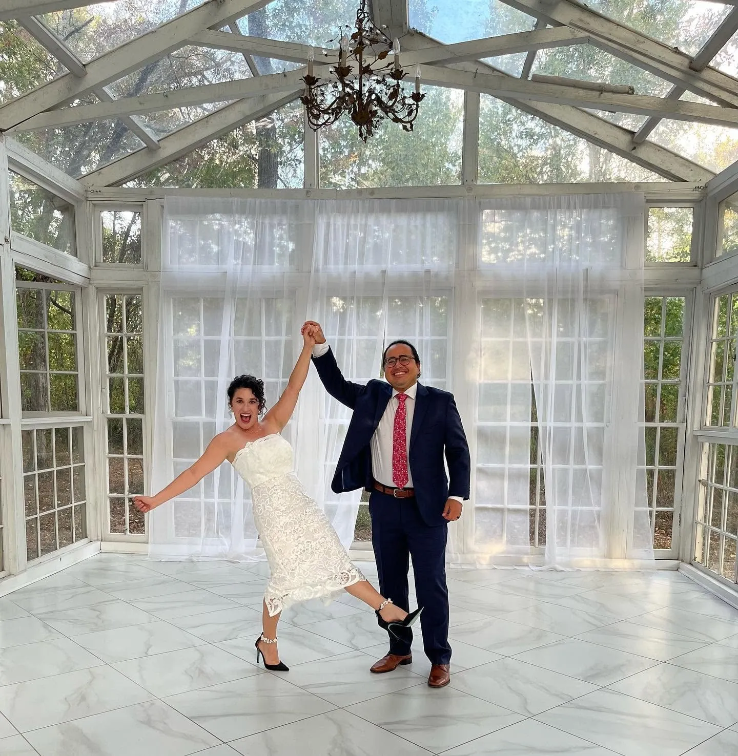 Newlywed couple celebrating together in a bright glass-walled venue